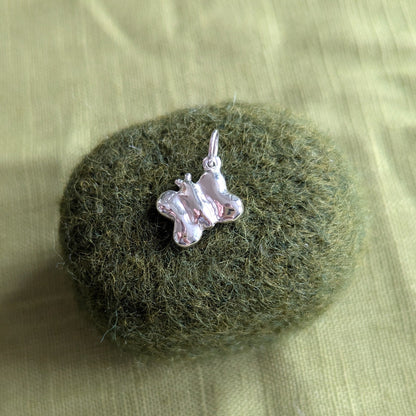 Small  silver butterfly pendant on a textured green surface
